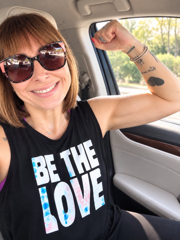Kristina smiling in sunglasses and flexing her arm in a black tank top